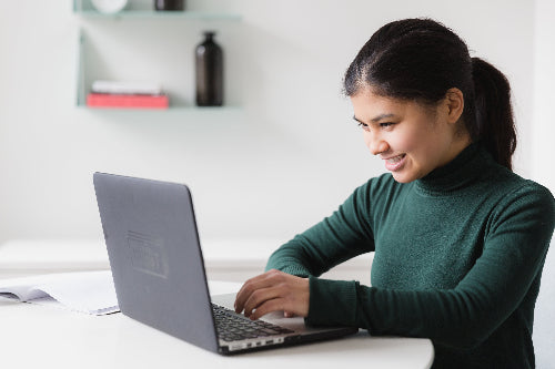 Woman using a laptop at a desk in a home office setting. signing up for Natural Action Newsletter