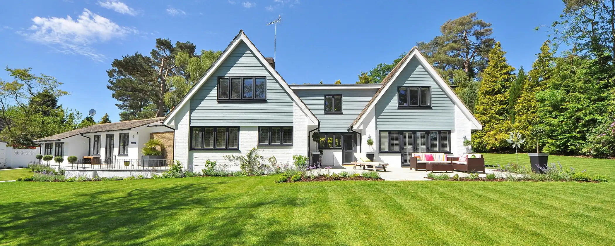 Two-story house with a green lawn and trees in the background using Next-Level Natural Action Water Filtration 
