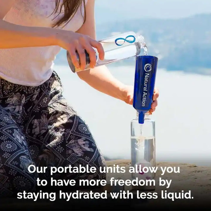 Person pouring water into a blue 'Natural Action' Portable unit into a glass with a scenic background.
